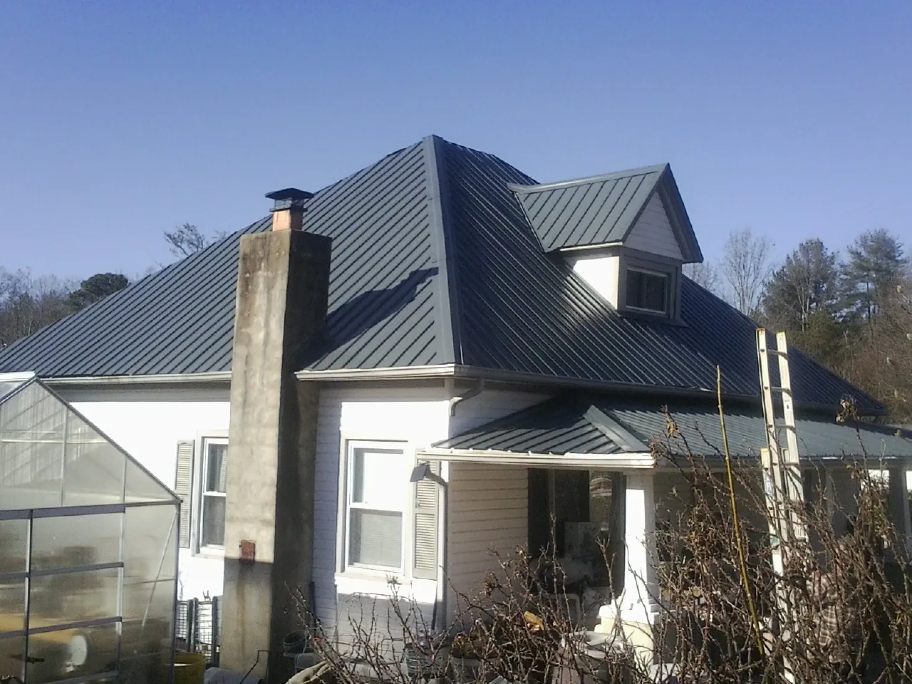 Dark blue standing seam metal roof on a white farmhouse with dormer — Slate & Tile Roof Repair by Roofing Brothers in Northampton