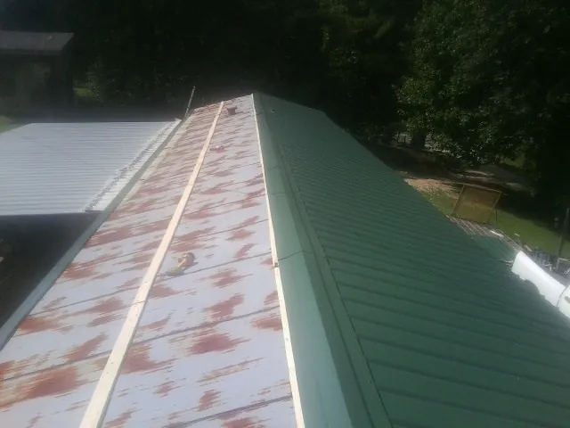Old rusted panels beside newly installed green metal roofing — Wind Damage Roof Repair by Roofing Brothers in Northampton