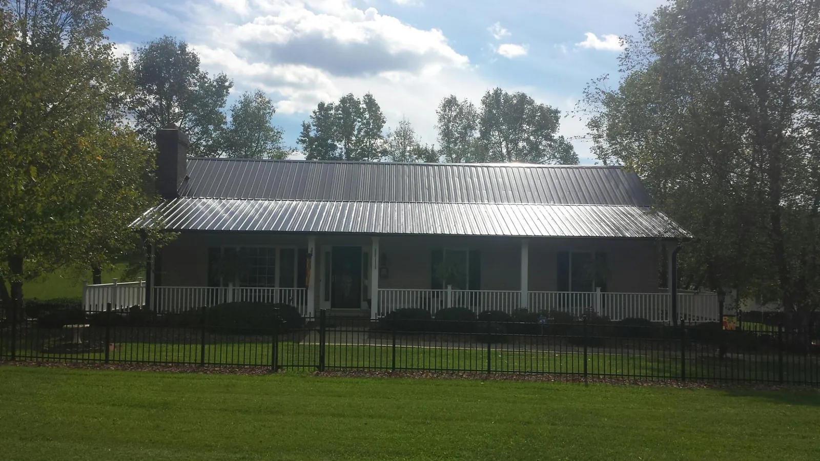 Gray metal roof on a brick ranch with a full width front porch — Gutter Guard Installation work by our crew in Northampton