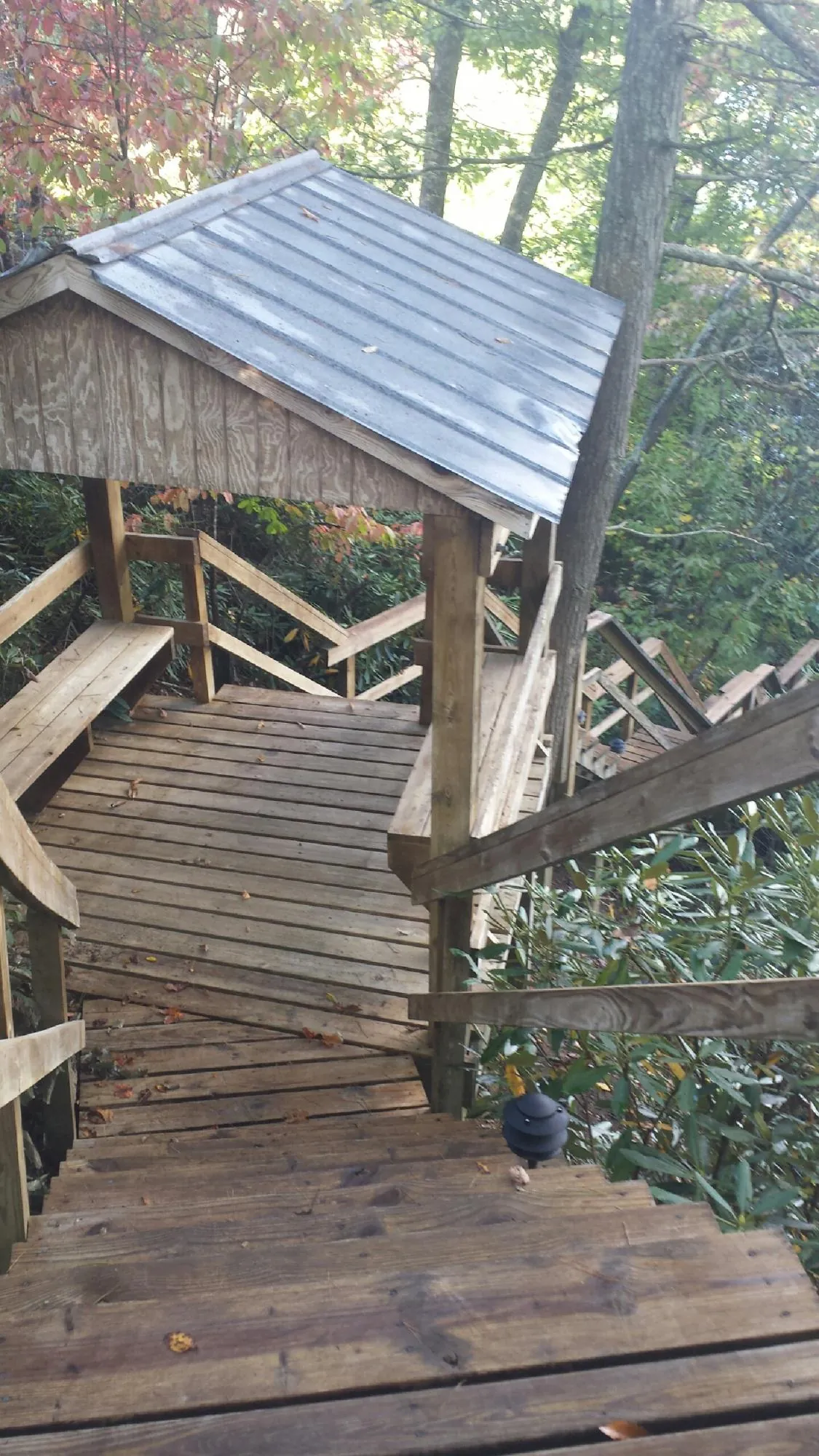 Metal roofed shelter over wooden steps on a wooded walkway — Skylight Repair & Installation work by our crew in Northampton