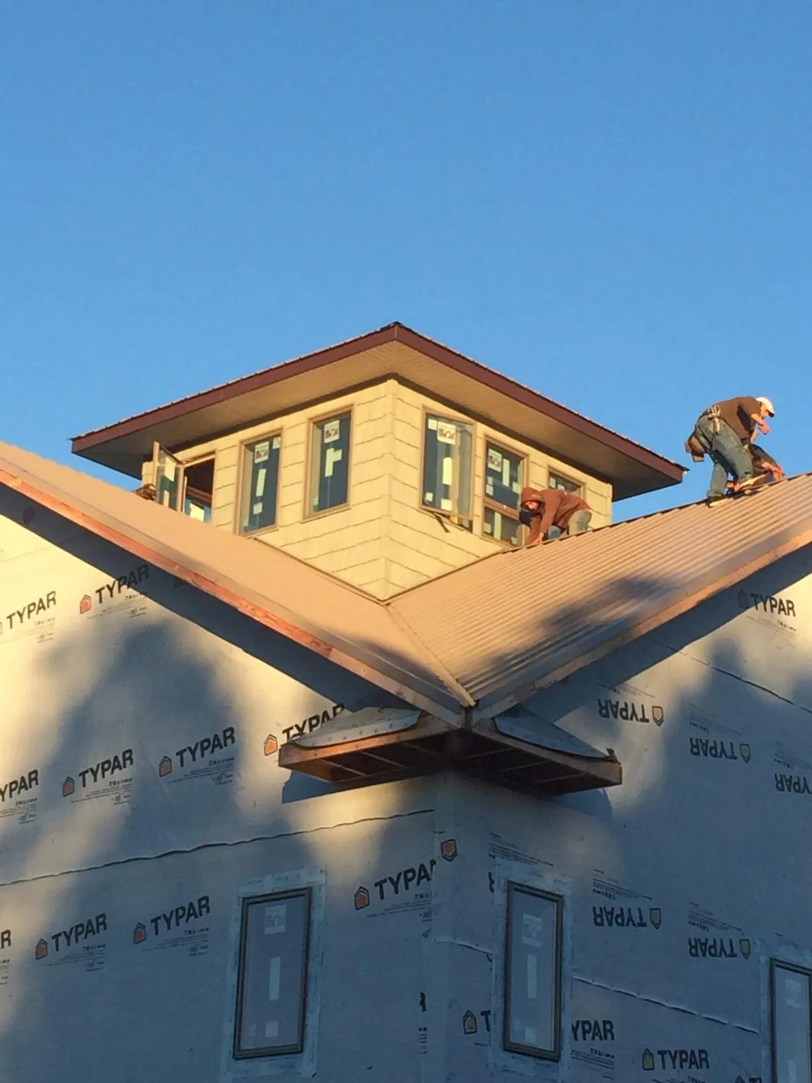 Roofers working around a rooftop cupola on a new metal roof at sunset — Roof Waterproofing in Northampton by Roofing Brothers